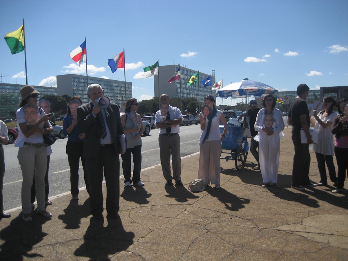 Brazilian Congressman Luiz Couto addresses human rights campaigners in Brasilia, carrying masks depicting the seven imprisoned Iranian Baha'i leaders.