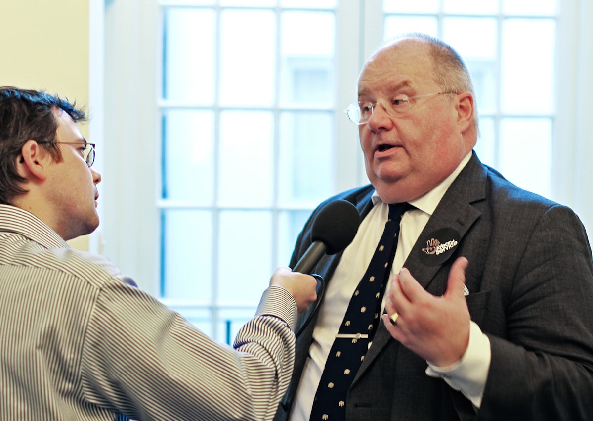 UK Secretary of State for Communities and Local Government, Eric Pickles MP, answers questions from a radio reporter about "A Year of Service," a government-sponsored initiative to encourage voluntary service by the UK's nine major faith communities. The launch and first volunteering day of the program was held at the national Baha'i center in London on 28 February 2012.