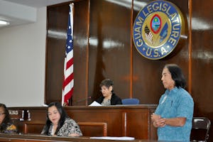 رئيس مجلس، جودیث وانپت – وسط– در حال سخنرانی در مجلس گوآم طیّ رأیگیری در مورد محرومیت از دسترسی به آموزش عالی در ایران. رأیگیری که به تصویب با اکثریت ۱۴ به ۰ منتهی شد، روز ۸ اردیبهشت ۱۳۹۱ (۲۷ آوریل ۲۰۱۲) برگزار شد.