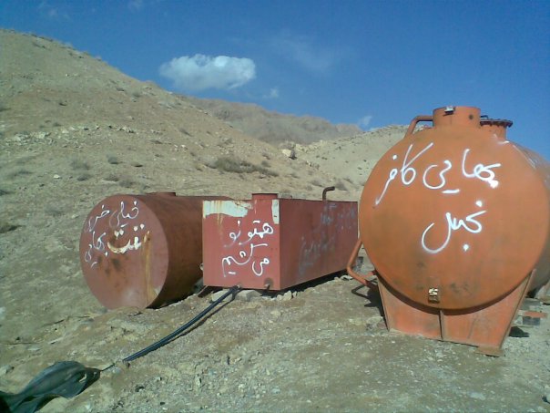 Anti-Baha'i graffiti sprayed on steel water drums and tanks at the Semnan Baha'i cemetery. The graffiti, when translated into English, describes Baha'is as "filthy pagans" and threatens, "We will kill you all."
