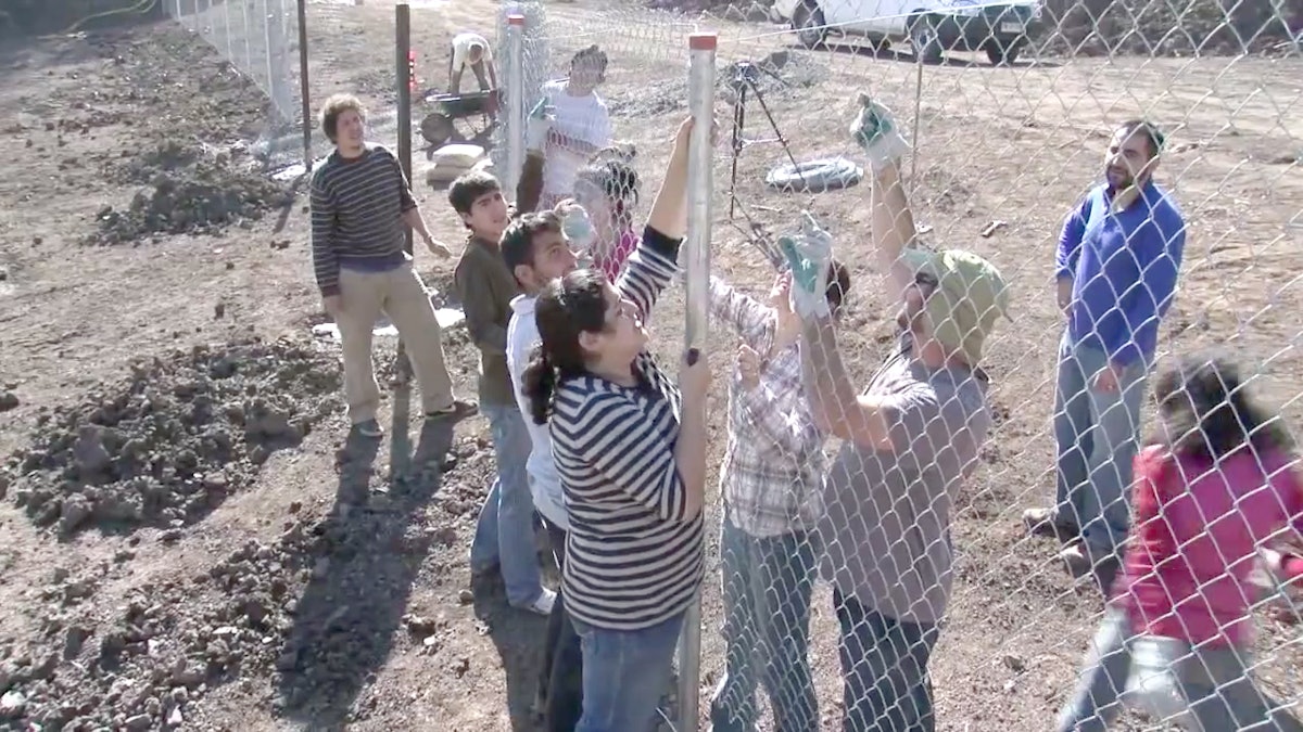 An image from the video newsreel, "Progress on the Construction of the Baha'i House of Worship for South America," depicting volunteers erecting a fence around the site in Peñalolén, Santiago. The video is now available for viewing online.