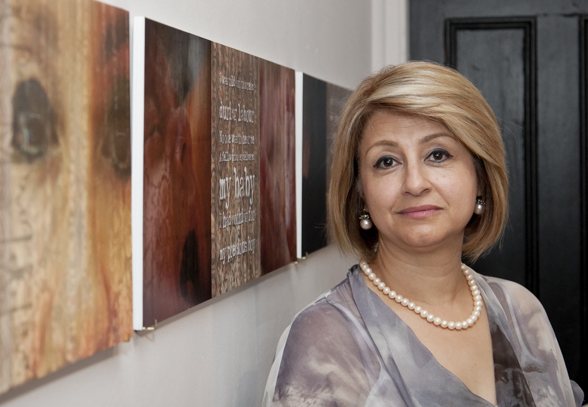 Zhila, an Australian-Iranian Baha'i, pictured in front of the artwork "Cell Block 8" which tells her story. The work, by photographer Leila Barbaro and writer Maryam Master, recounts how Zhila gave birth to her son while incarcerated for her beliefs in Tehran's notorious Evin prison.
