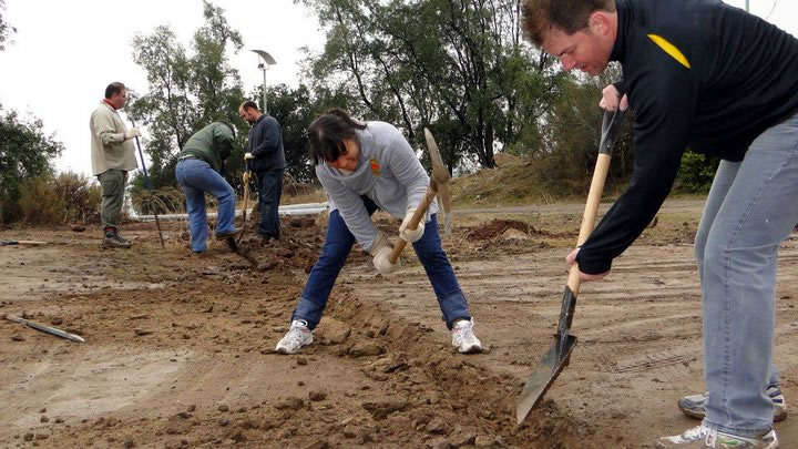 Young people participate in efforts to prepare the ground for a security fence around a temporary office building and storage area for the Baha'i House of Worship currently under construction.