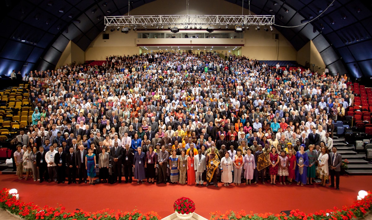 A group photograph of the 11th International Baha'i Convention. The bouquet of red roses in the foreground noted the absence of delegates from Iran.