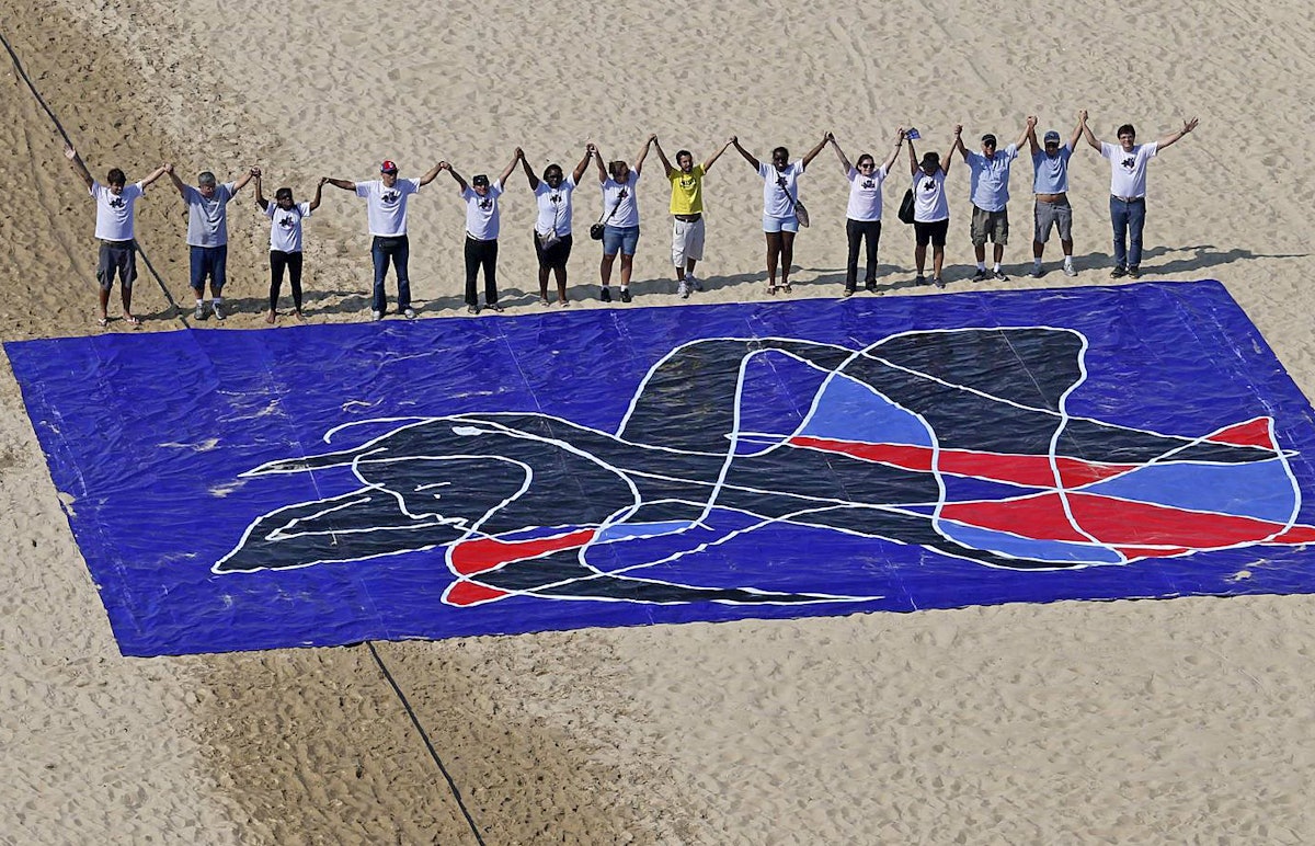 In Rio de Janeiro, Brazil, participants in the Five Years Too Many campaign lined up on Copacabana Beach on Sunday, 5 May 2013, behind a mural created by noted Brazilian artist, Siron Franco.