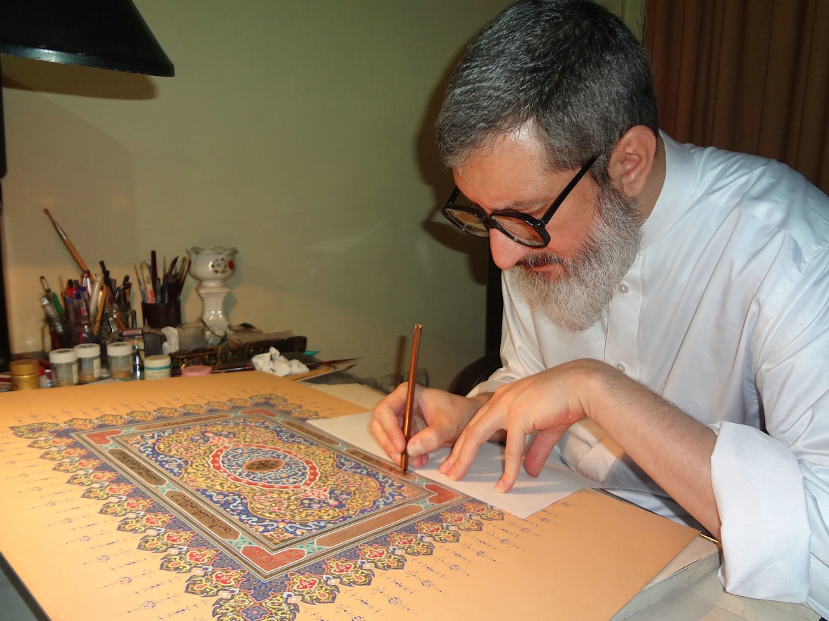 Ayatollah Abdol-Hamid Masoumi-Tehrani perfecting an illuminated work of calligraphy. The words used in this piece are from the writings of Baha'u'llah.