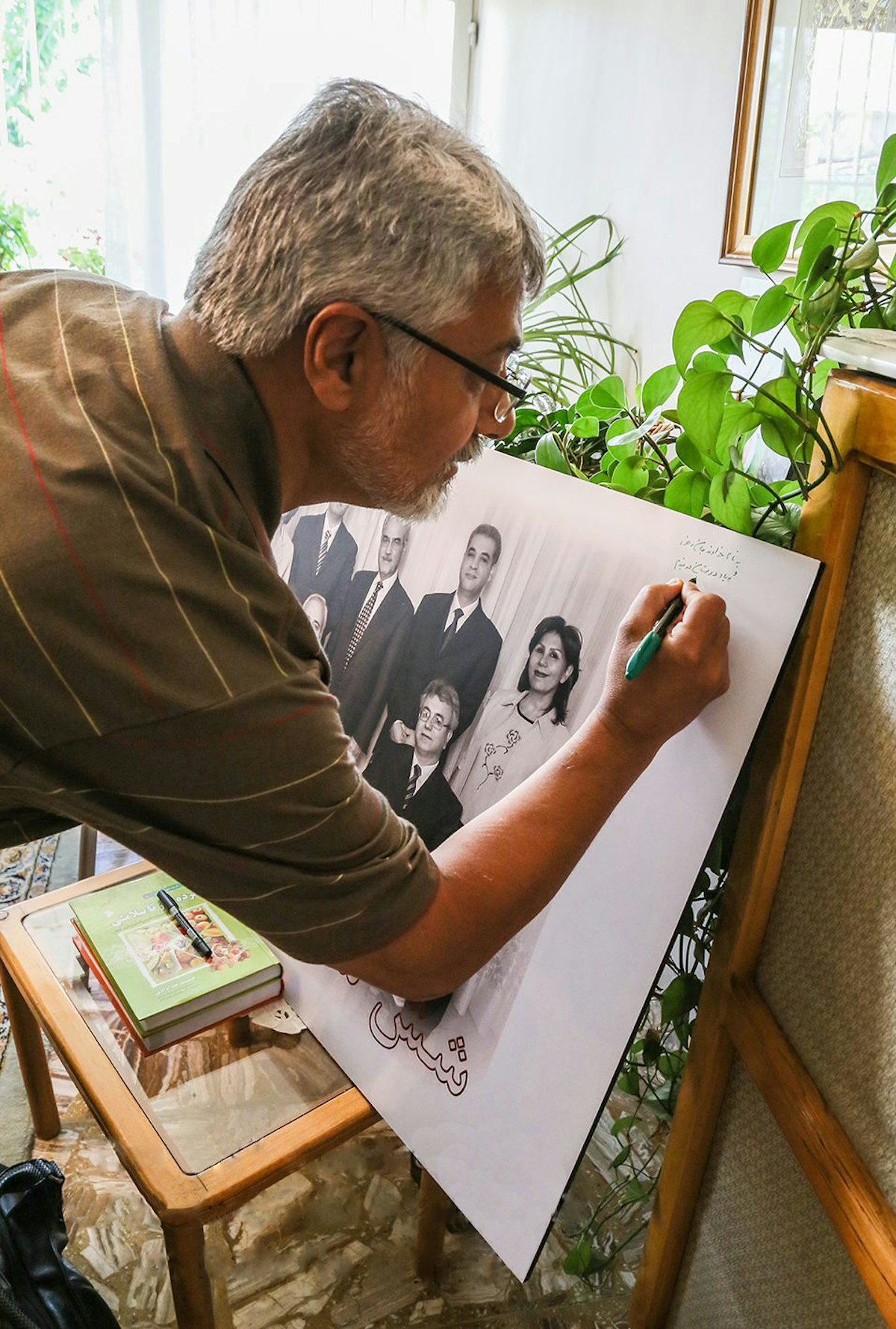 Issa Saharkhiz, a prominent Iranian journalist, signs a photo of the seven former Baha'i leaders in Iran.