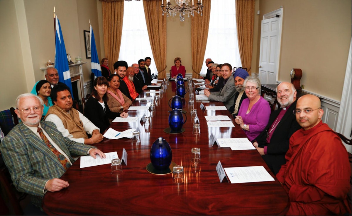 First Minister of Scotland Nicola Sturgeon sits at the head of a table at which gathered representatives of the country's religious groups, 8 September 2015 in Edinburgh. Baha'i representative Jeremy Fox is seated front left.