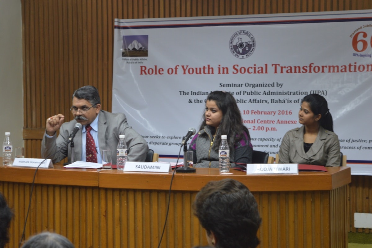 سرلشگر دلاور سینگ (Dilawar Singh) (سمت چپ)،‌ رئیس کلّ وزارت ورزش و جوانان دولت هندوستان در حال سخنرانی در مورد نقش جوانان در روند جامعه‌سازی به عنوان یکی از اعضای میزگرد. سادامینی پاندی (Saudamini Pandey) مدیر پروژه و رئیس مؤسسۀ غیر انتفاعی (NGO) (در وسط) و پوجا تیواری (PoojaTiwari)، نمایندۀ جوانان بهائی (سمت راست).