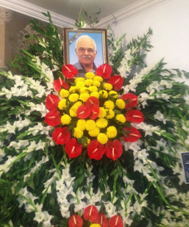 A photograph of Farhang Amiri placed atop a floral bouquet at his funeral