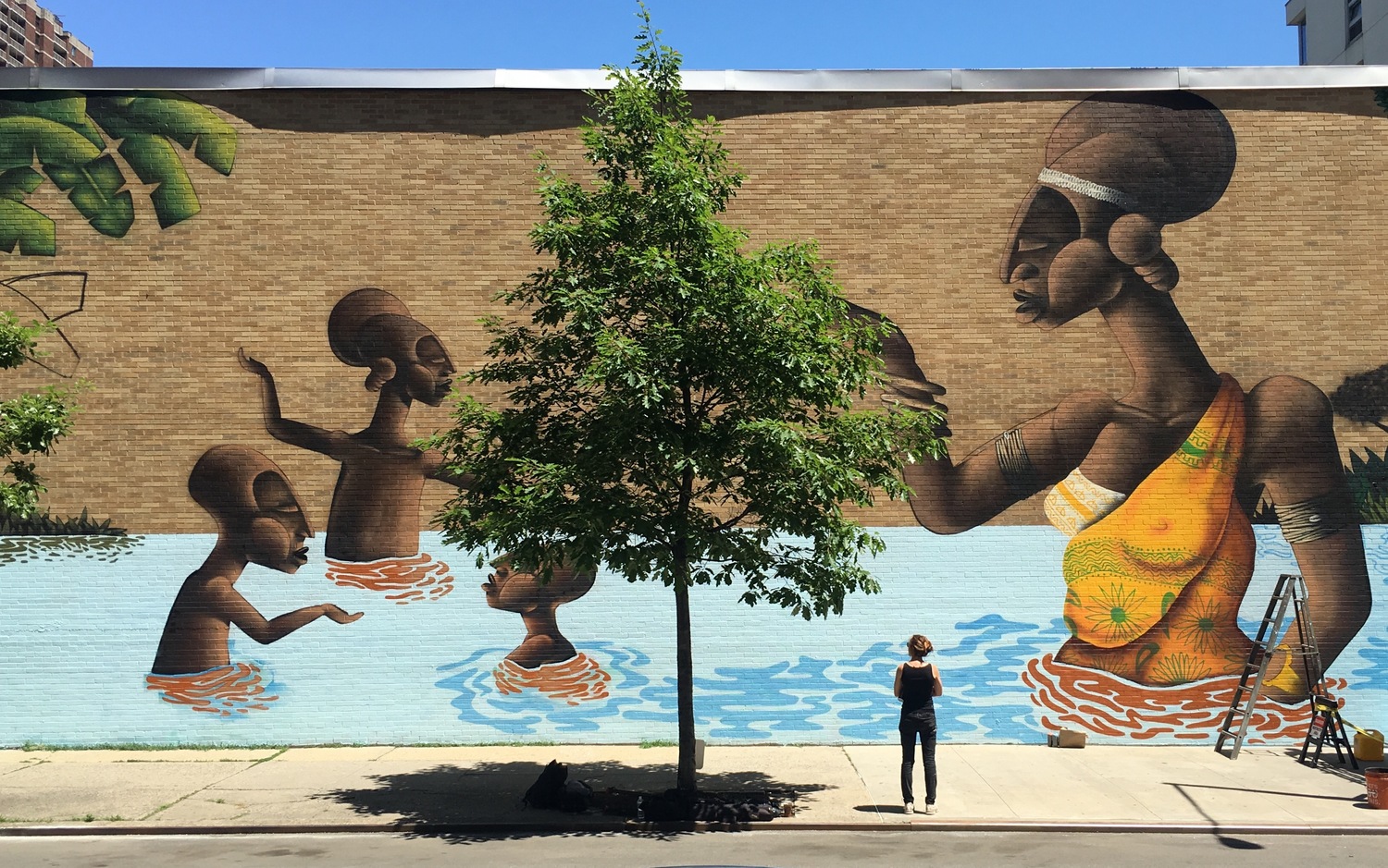 This mural by Brazilian artist Alexandre Keto depicts a mother watching over and educating her children. The setting evokes many themes—education equality, care for the planet, and bridging communities of color and suffering from around the world. The mural is painted on the side of the PS7 School in East Harlem.