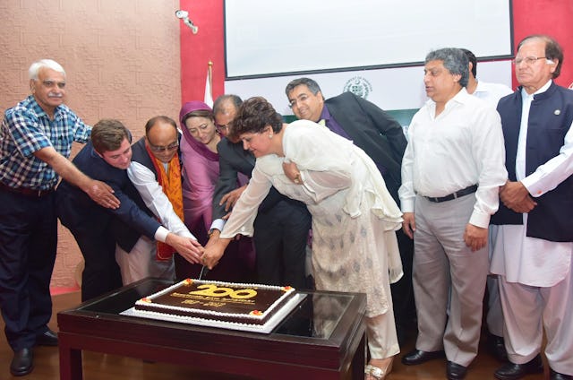 Member of Parliament Asiya Nasir and other speakers cut cake at an event honoring the 200 year anniversary of Baha'u'llah's birth.