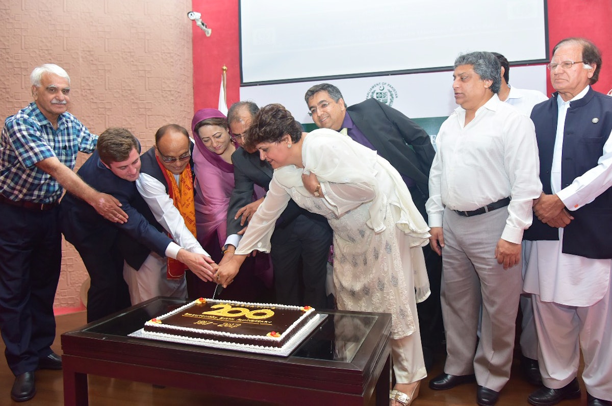 Member of Parliament Asiya Nasir and other speakers cut cake at an event honoring the 200 year anniversary of Baha'u'llah's birth.