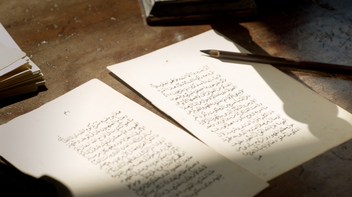 A reed pen belonging to Baha’u’llah sits atop a facsimile of one of His Tablets.
