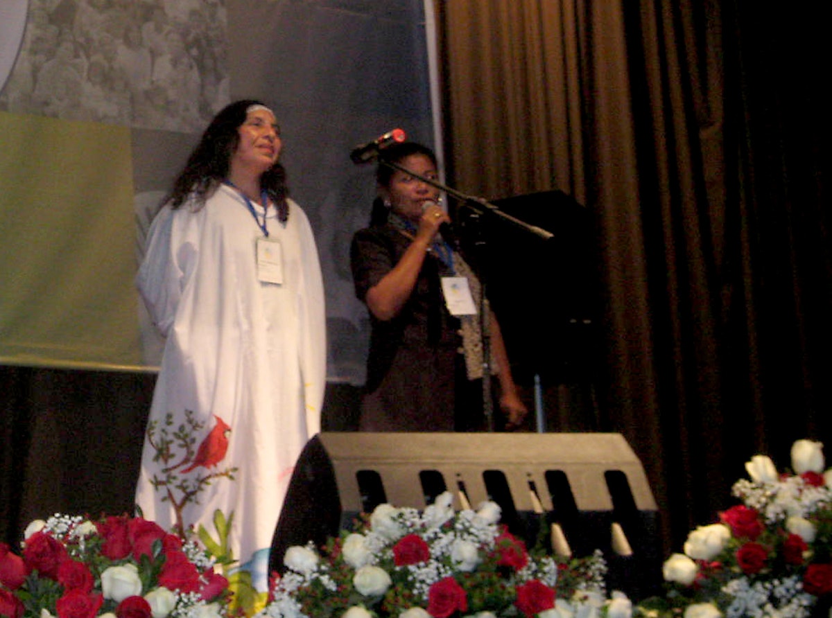 In a gown typical of her native Guajira region, one of the Colombian participants stands onstage at the conference in Quito to share experiences. A bus carrying 14 Baha’is from the Guajira crashed on the first leg of their long trip, yet only one of them had to return home.