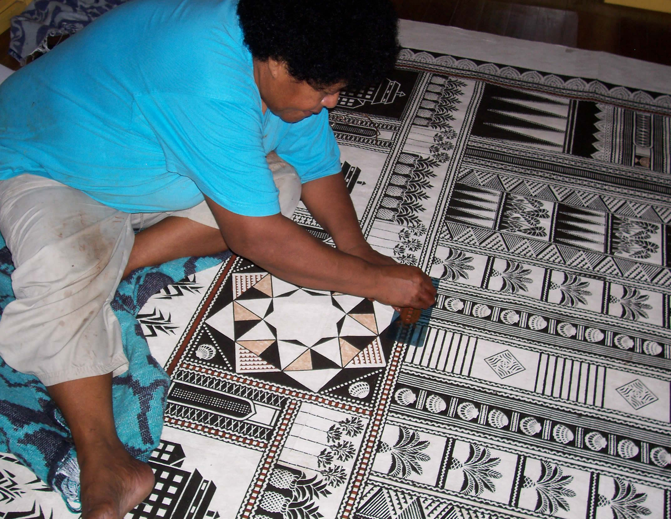 Bale Jione paints the pattern onto the bark cloth using the stencils that she and her collaborators made.