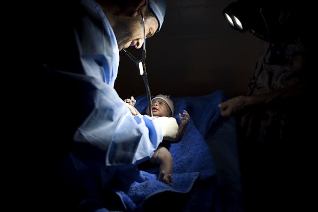 A volunteer doctor examines Tina Rose Wome shortly after her birth at a Baha'i school in Port-au-Prince. A medical team from Canada and the United States had set up a makeshift clinic at the school, and all 18 team members were on hand for the arrival of the baby, named after Dr. Tina Edraki and Rose Cabot, the doctor and nurse who delivered her. (Baha'i World News Service photographs)