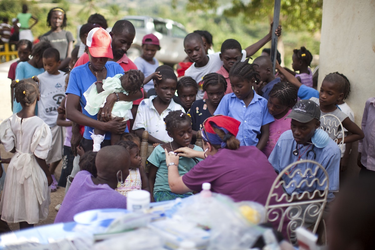 Dr. Munirih Tahzib, a pediatrician from Hoboken, New Jersey, treats a child next to a collapsed school in a village outside of Port-au-Prince. At a separate stop at an orphanage, Dr. Tahzib and other volunteers examined 150 children in need of medical attention.