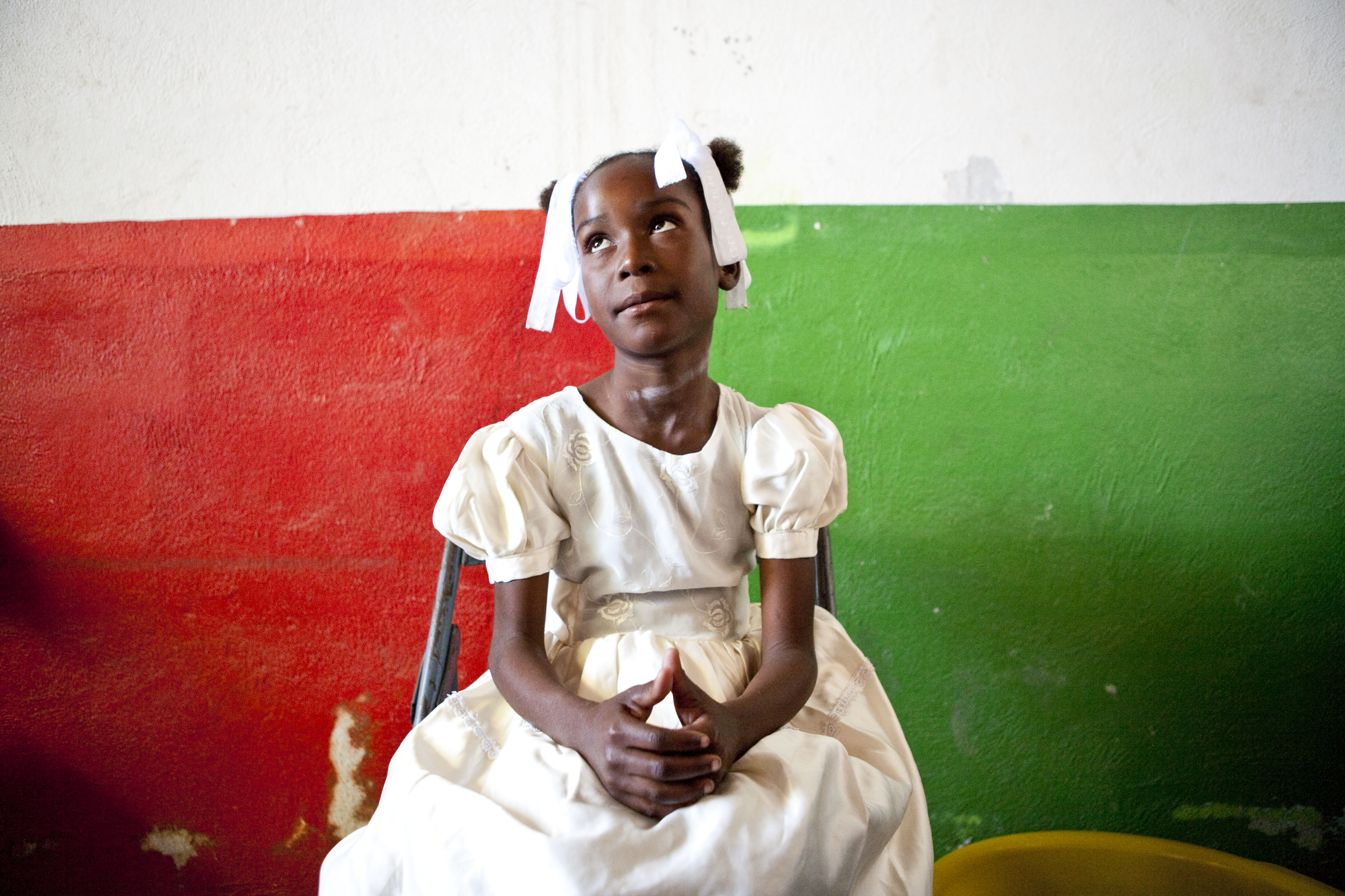 A young girl waits to see a doctor at a makeshift clinic on the outskirts of Port-au-Prince. The doctors in the team staying at the Zunuzi Baha'i school treated patients there and also traveled to other localities, including hospitals, orphanages, and temporary medical stations set up in nearby villages.
