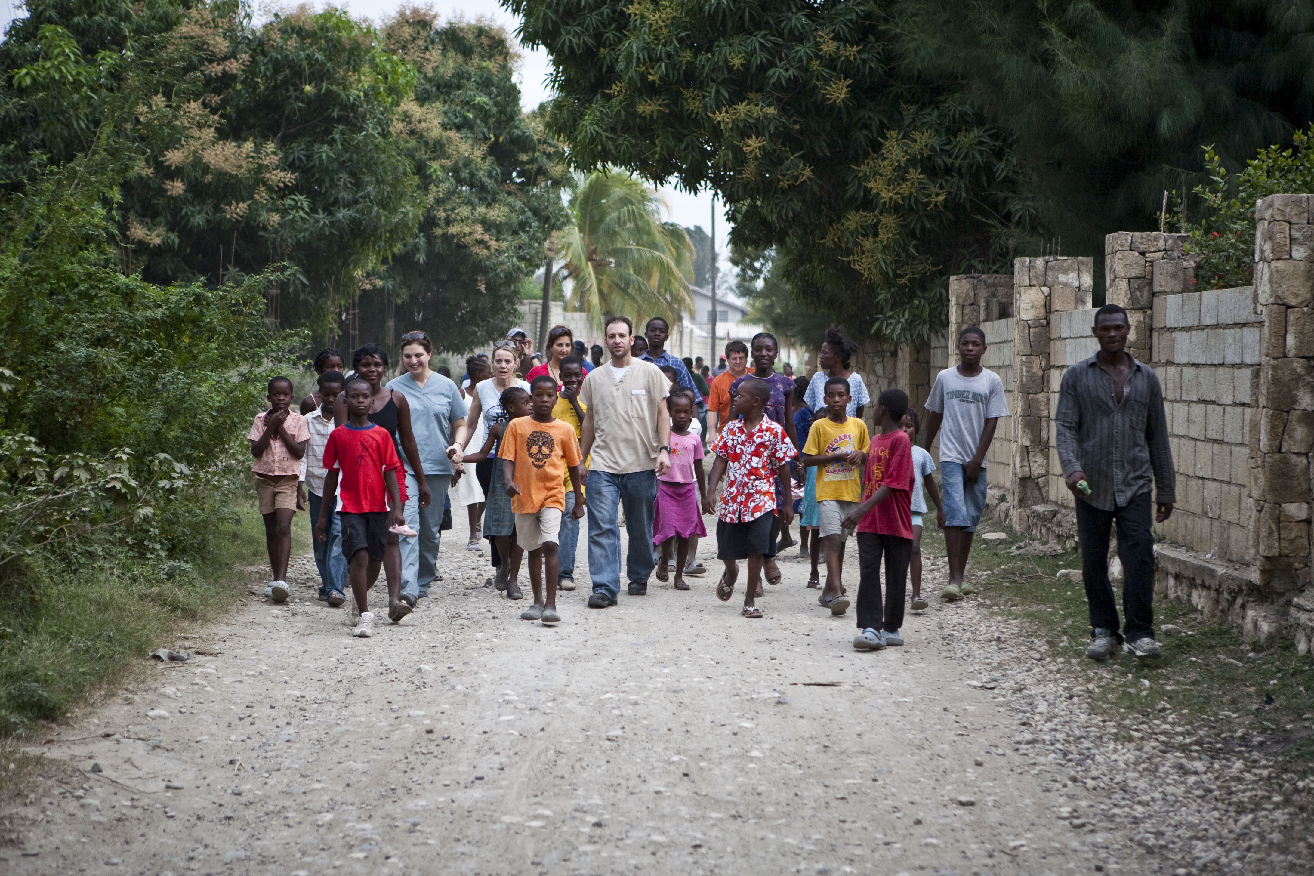 Local residents accompany two visiting physicians, Dr. Munirih Tahzib and Dr. Jason Hitner, as they arrive in a neighborhood on the outskirts of Port-au-Prince. Now back home in the United States, these two doctors and others are consulting about how they might continue to support the Haitians in their efforts to rebuild their country.