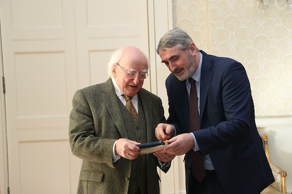 President Higgins accepts a gift from the Baha’i community—a copy of a newly published translation of some Baha’i prayers into the Irish language. There has been a nation-wide effort to promote the Irish language this year, and President Higgins thanked the Baha’is for the timely and positive contribution to these efforts.