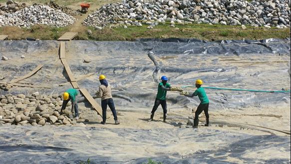 Placing boulders at the base of one of the man-made lakes on the grounds of the Temple in Norte del Cauca.