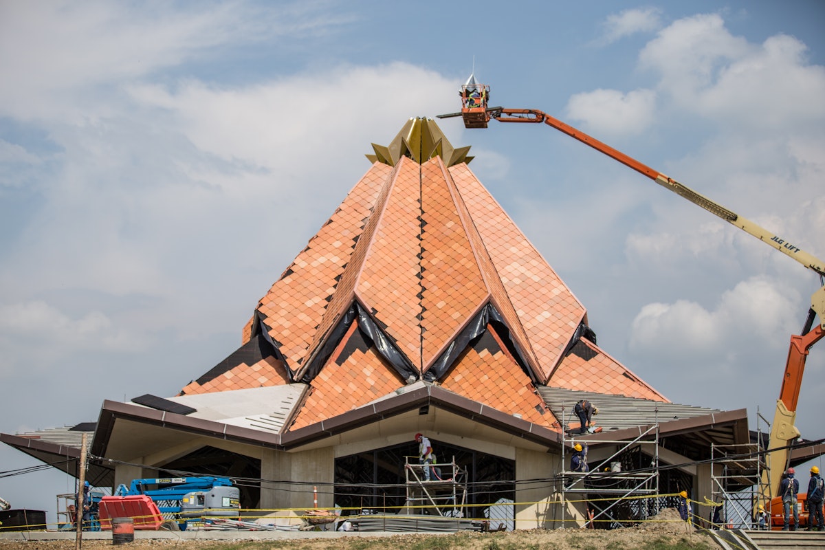 Unos trabajadores colocan la corona en la parte superior del tejado de la casa de adoración local en Norte del Cauca, Colombia.