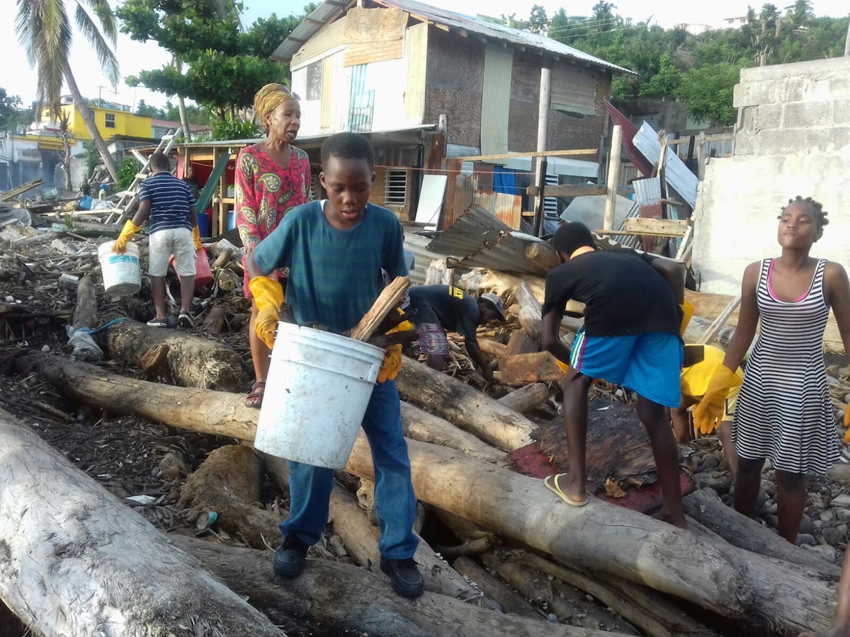 همسایه‌ها در محلۀ نیوتاون شهر روسو در حال کمک به جمع‌آوری آوار به جای مانده از طوفان در خلیج.