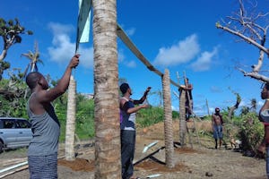 Youth and adults work together to build a greenhouse in the Kalinago territory.