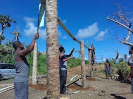 Des jeunes et des adultes travaillent ensemble à la construction d’une serre sur le territoire kalinago.