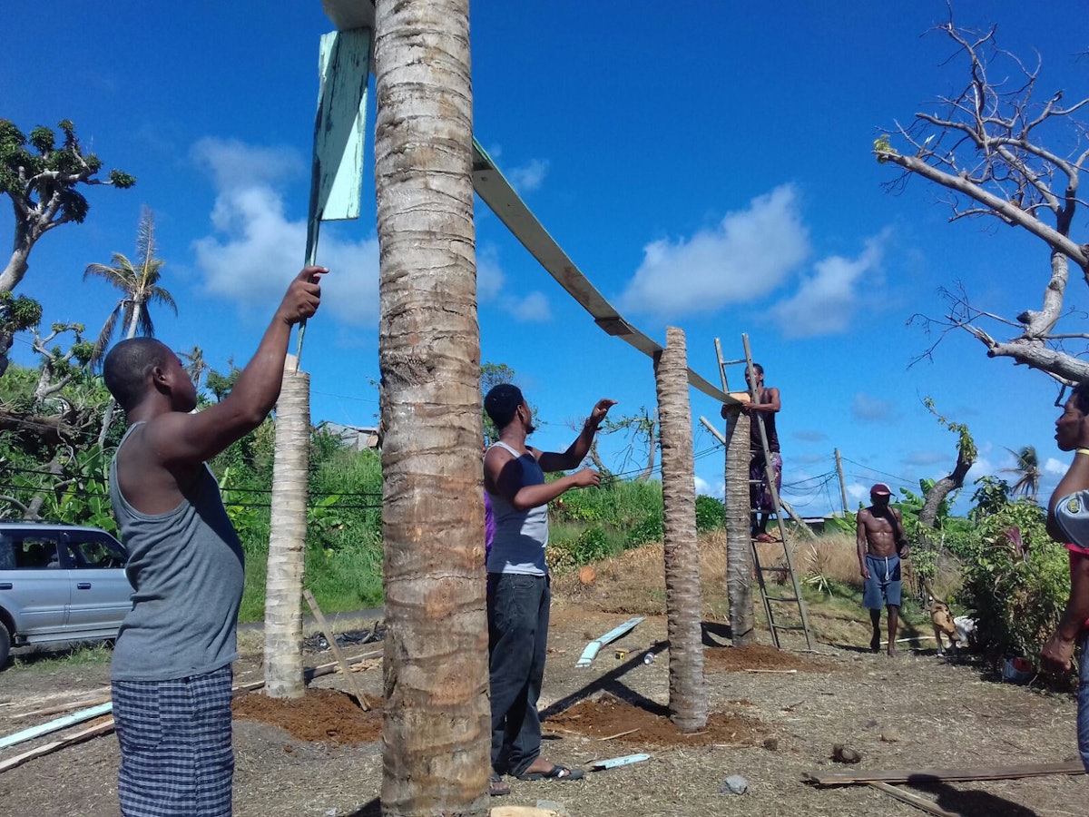 Des jeunes et des adultes travaillent ensemble à la construction d’une serre sur le territoire kalinago.