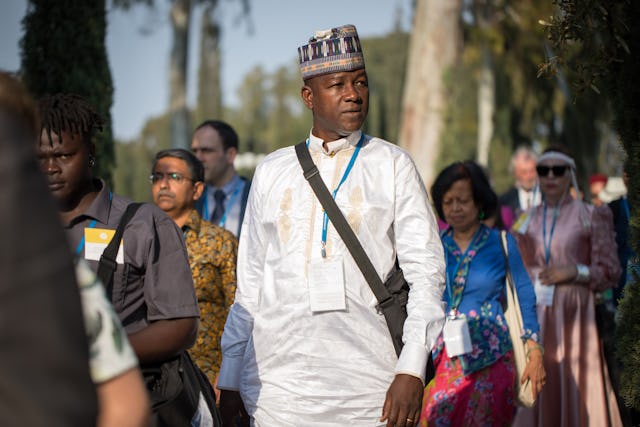 Des participants à la célébration du neuvième jour du Ridván marchant ensemble sur un chemin entourant le lieu le plus sacré pour les bahá’ís : le tombeau de Bahá’u’lláh.