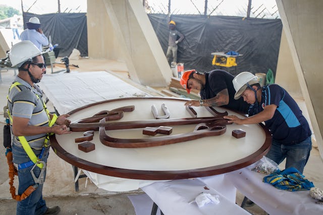 Carpenters from the firm that carved the Greatest Name symbol prepare it to be raised to the apex of the dome of the local House of Worship in Agua Azul, Colombia.