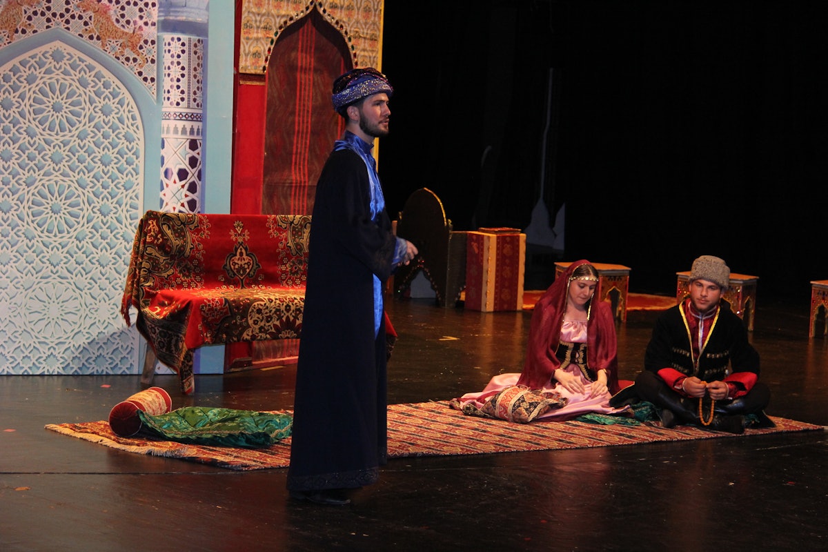 An actor playing Tahirih’s cousin, who played an important role in connecting her to the intellectual and religious thought movements in society, speaks with two other relatives of Tahirih in a scene of the play.