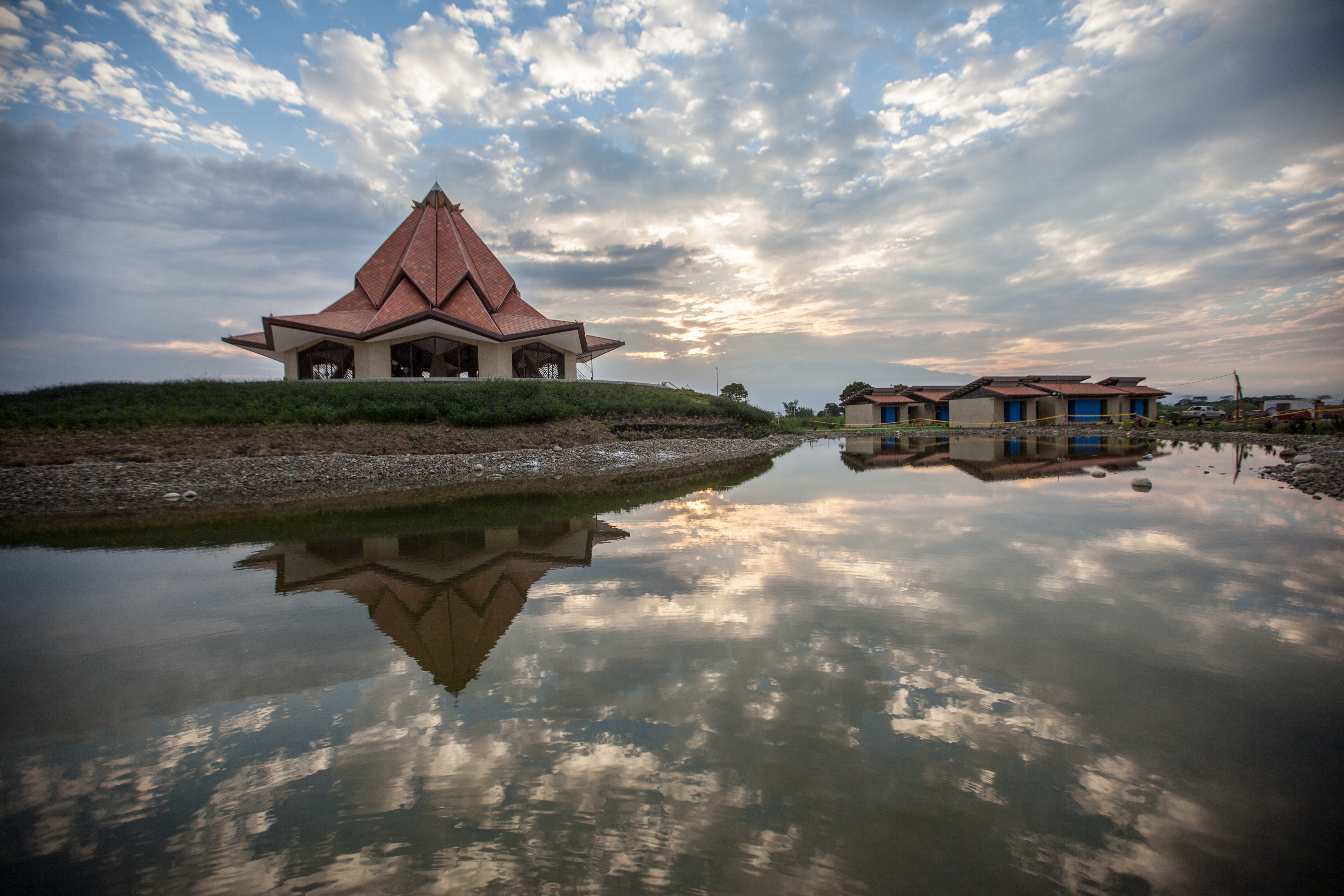 انعکاس تصویر معبد و برخی از ساختمان‌های جانبی آن در یک برکه آب.