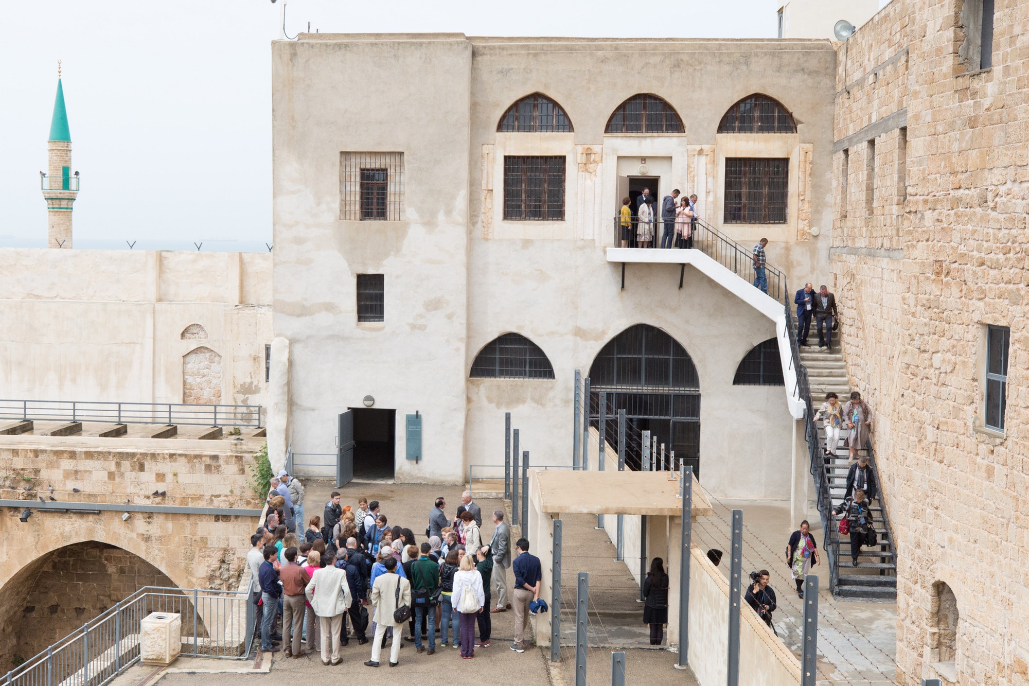 This recent photo shows the staircase leading to the prison quarters where Bahá’u’lláh and His companions were kept for more than two years. A group of Baha’is are leaving after a visit to the site.