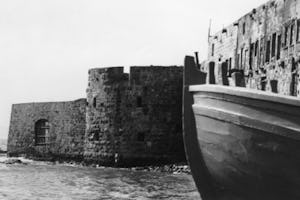 This video shows the present-day old city of ‘Akká. The prison where Bahá’u’lláh was held is the large structure toward the top of the frame, to the left of a blue dome.