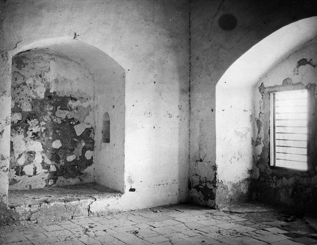 این تصویر از سال ۱۹۲۱ سلول زندانی که حضرت بهاءالله برای بیش از دو سال از ۱۸۶۸ تا ۱۸۷۰ در آن زندانی بودند را نشان می‌دهد، در اینجا بود که ایشان برخی از نامه‌های خطاب به پادشاهان و رهبران دنیا را مرقوم داشتند.