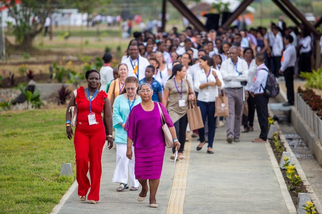 People walk past the Temple’s ancillary buildings for their visit to the interior of the central edifice. The group was led by Carmen Elisa de Sadeghian, the representative of the Universal House of Justice to the gathering (Front row, right).