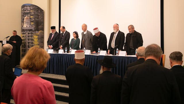 Le père Yousef Yakoub (à gauche) récitant la prière de saint François d’Assise en arabe, anglais et hébreux dans le recueillement des membres de l’auditoire et des panélistes (à partir de la gauche) : l’émir Muhammad Sharif Odeh, Shervin Setareh, secrétaire générale adjointe de la Communauté internationale bahá’íe, le rabbin Naama Dafni-Kelen, l’évêque Michel Dubost, le cheik Jaber Mansour, le rabbin David Metzger et le cheik Rashad Abo Alhigaa.