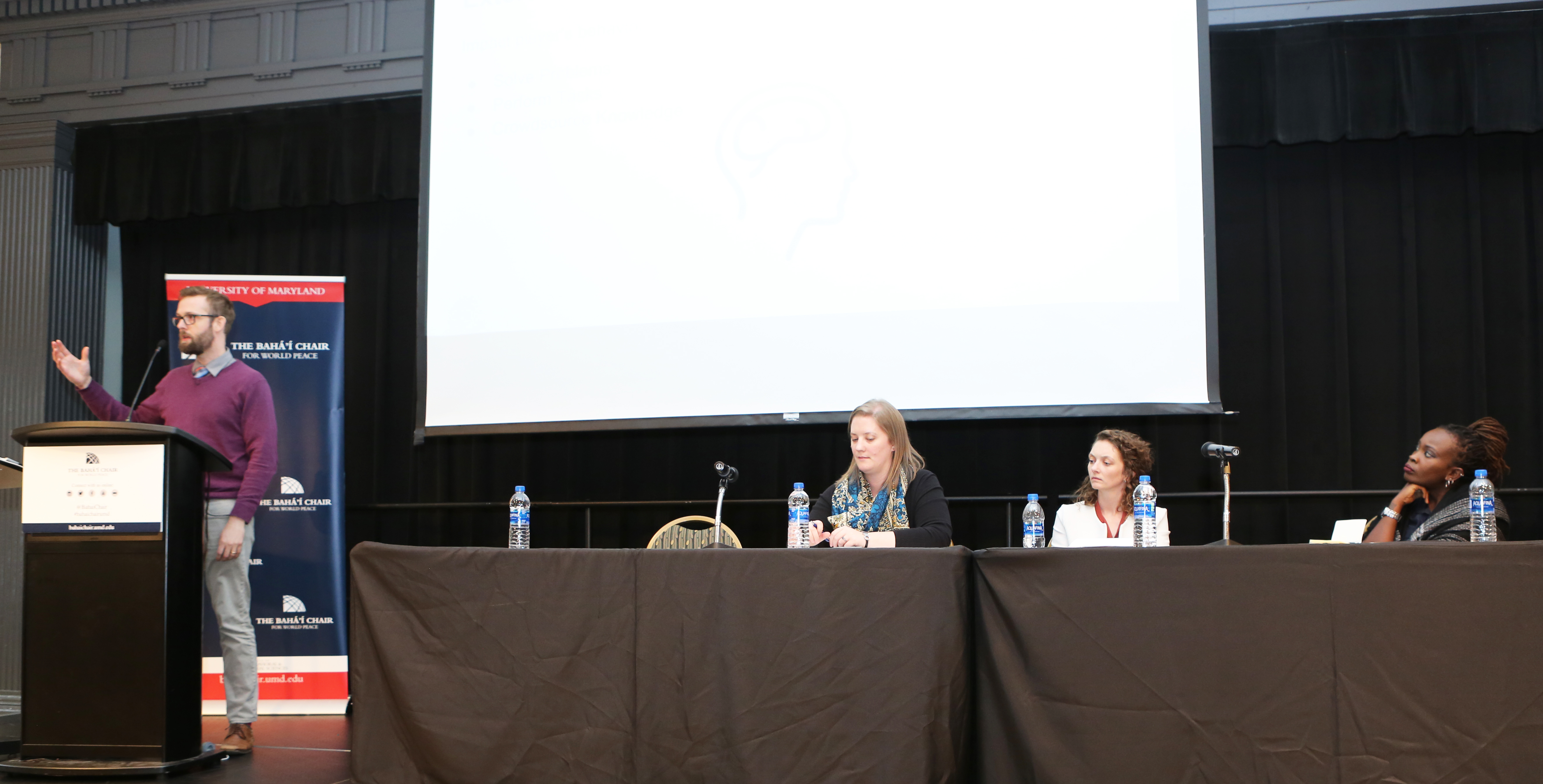 Derek Caelin, of Counterpart International, speaks during a panel session on peace and technology while moderator (from left) Kate Seaman, with the Baha’i Chair, and fellow panelists Maude Morrison, of Build Up, and Nanjira Sambuli, of the World Wide Web Foundation, listen.
