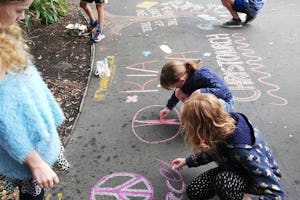 A group of young people draw chalk art on a sidewalk in Christchurch. A group of families involved in Baha’i community building activities in a neighborhood began the street art activity to inspire hope following the 15 March terror attacks.