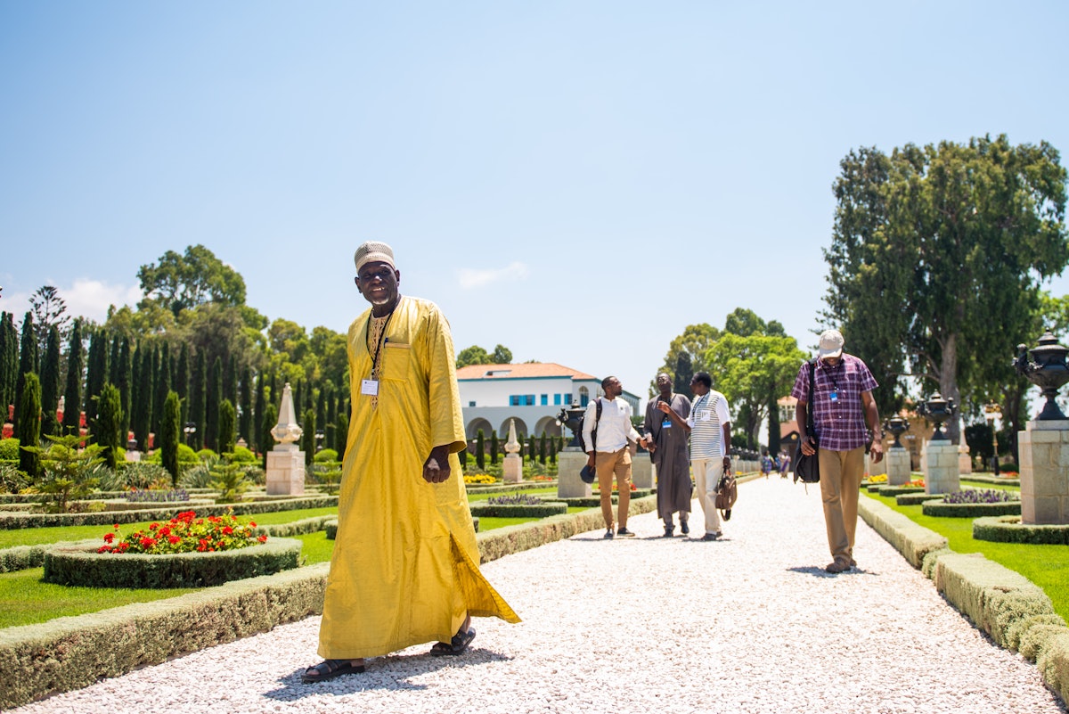 Varios peregrinos caminan por los jardines en Bahjí después de visitar el Santuario de Bahá’u’lláh.