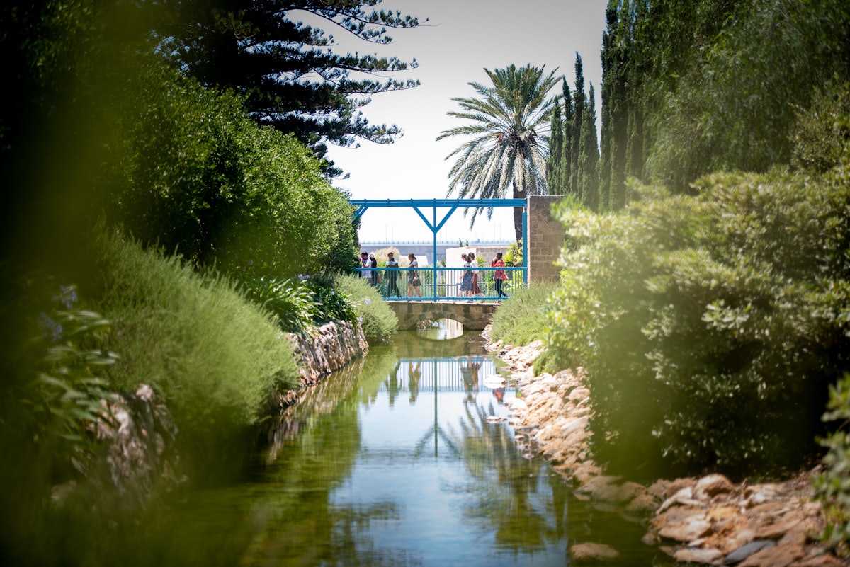 Pèlerins traversant le pont au-dessus d’un ruisseau restauré autour du jardin de Ridván à Acre.