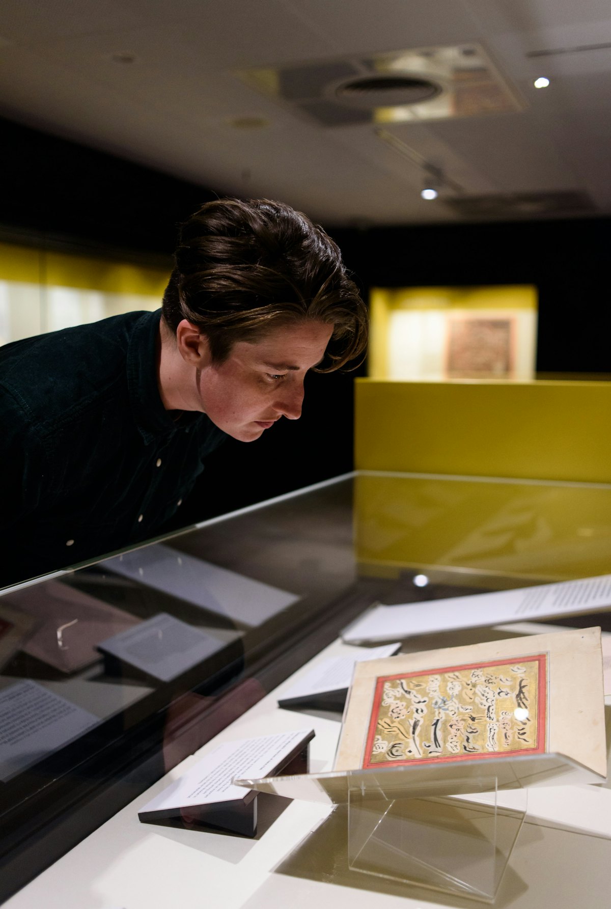 Un visiteur regarde des textes bahá’ís originaux que l’on peut voir à l’exposition sur les Écrits saints de plusieurs traditions religieuses. (Crédit photo : Richard Eaton, British Library Board.