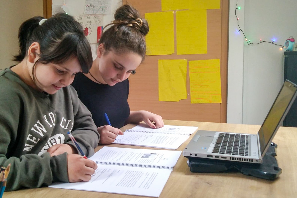 Dos hermanas de Bašelj, Eslovenia, participantes de un grupo de jóvenes dentro de los programas educativos bahá'ís que fomentan las capacidades para el servicio a la sociedad. Se conectan por internet con otros miembros de su grupo desde casa, siguiendo las directrices de salud pública.