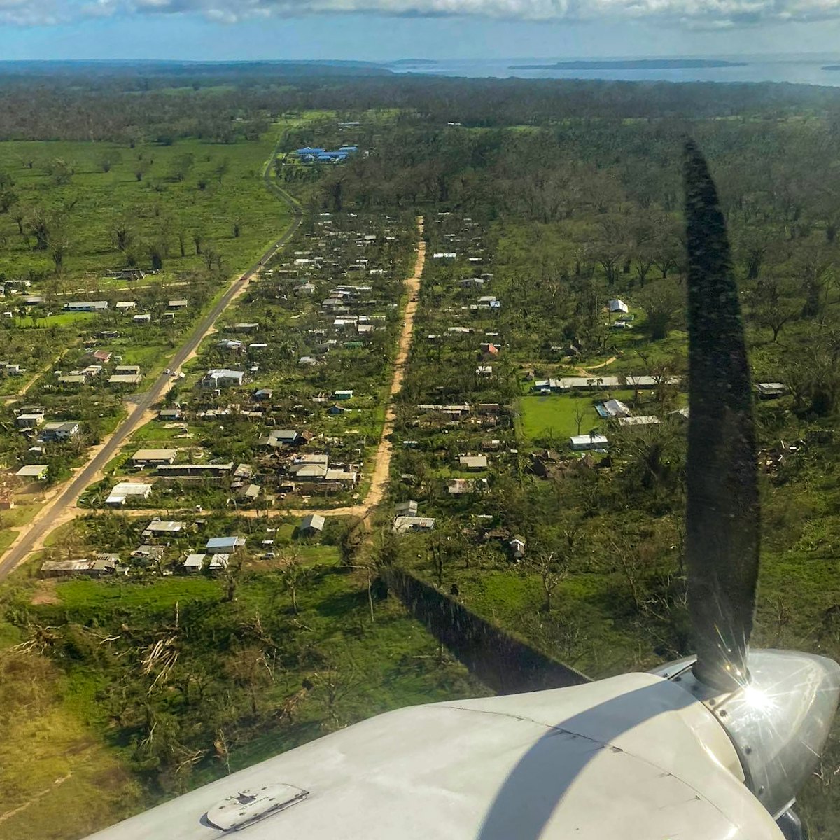 An aerial view of the effects of Cyclone Harold on the island of Espiritu Santo, Vanuatu, showing damaged buildings and stripped vegetation.