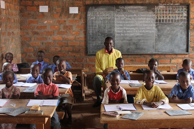 این عکس قبل از شرایط بحران سلامت کنونی گرفته شده است. یکی از کلاس‌های مدرسه‌ٔ محلی در بانگی در آفریقای مرکزی. «این مدارس ثمرهٔ تلاش مردم محلی- والدین و معلمین - به‌منظور فراهم آوردن آموزش باکیفیت برای کودکان است. این مدارس عناصر معنوی و آکادمیک را با هم می‌آمیزد و کودکان را با هدف مشارک در پیشرفت اجتماعشان تربیت می‌کند.»