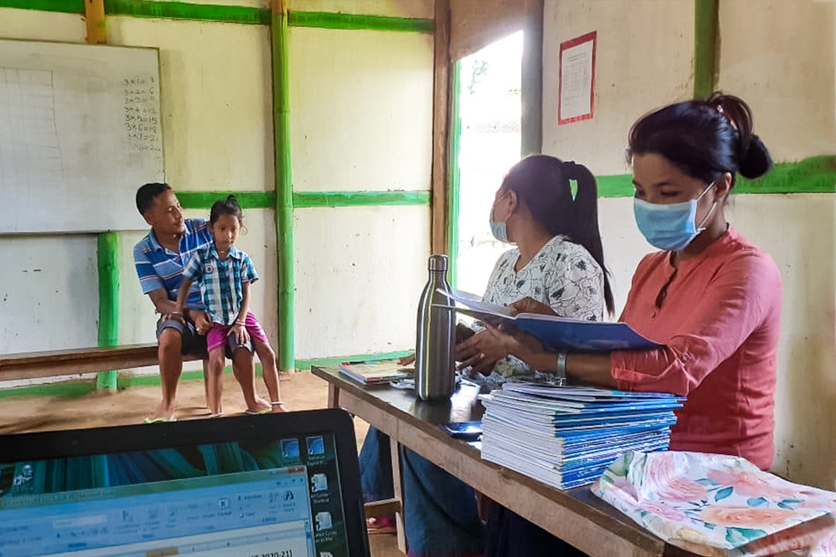 Teachers at a community school in Langathel, Manipur, India, distribute schoolwork to parents to carry out with their children at home as a precautionary measure during the health crisis.