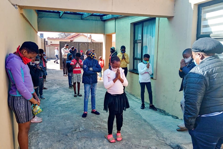 A group of youth in Soweto, South Africa, who have been participating in Bahá’í community-building endeavors seen here praying together.